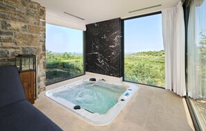 Ein Zimmer mit großem Fenster, Whirlwanne und Steinwand.