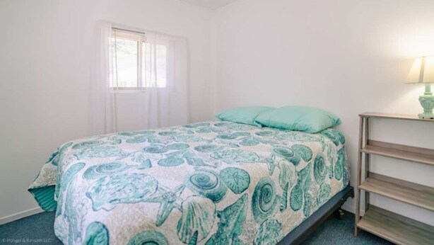 A bedroom with a bed, a window, a lamp, and a shelf.