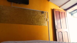 Une pièce comprenant un lit, une armoire en bois et un téléviseur fixé au mur.