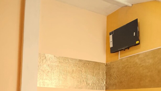 Une chambre d’hôtel avec un lit, un téléviseur fixé au mur et un mur décoratif à motifs.
