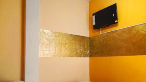 Une chambre d’hôtel équipée d’un lit, d’un téléviseur fixé au mur et d’un panneau décoratif mural.