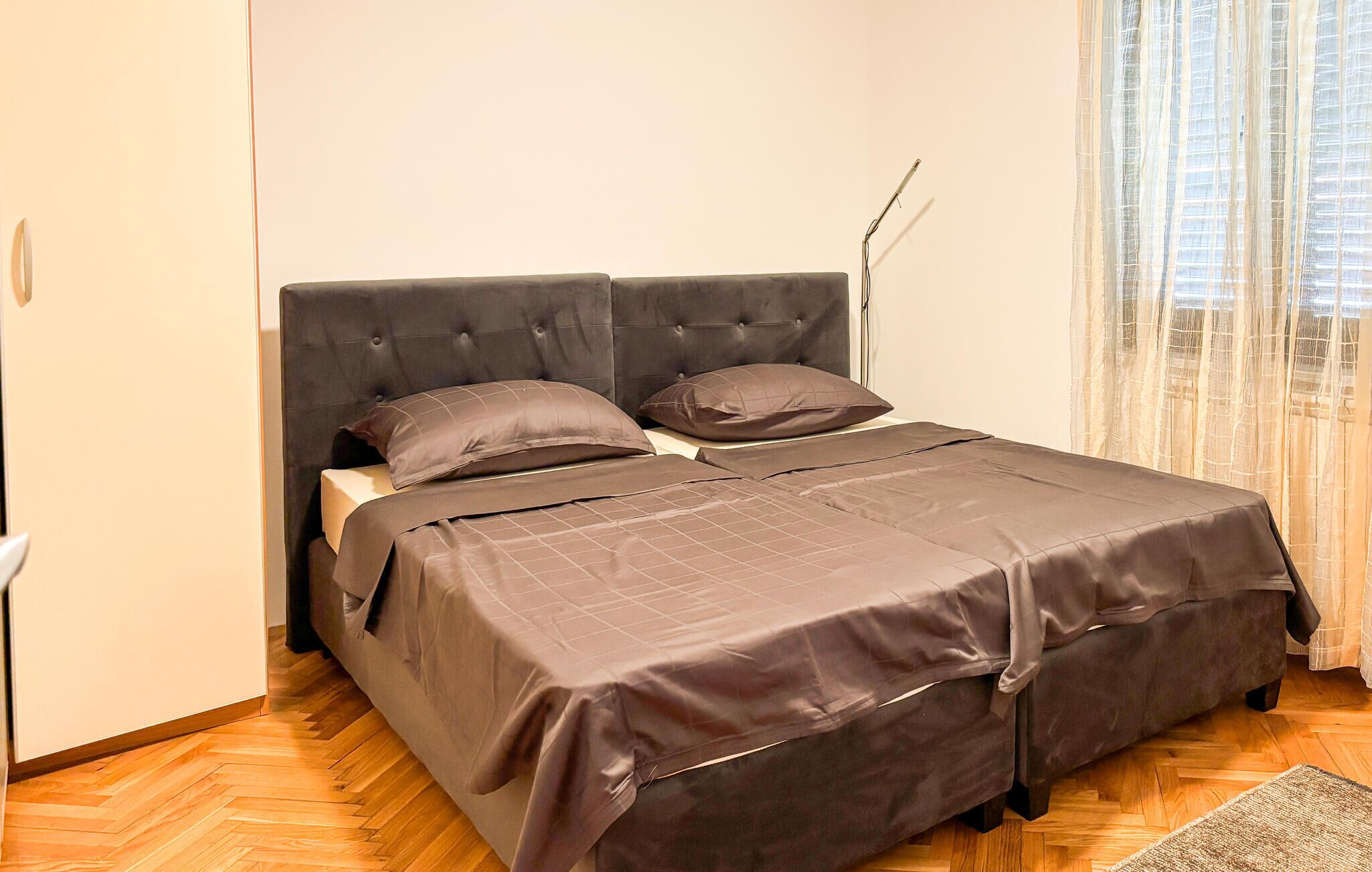A bedroom with a bed, a wardrobe, and a window with curtains.