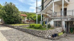 A courtyard with stone pathways, a building with a balcony, and a view of the surrounding area. - 3 bedroom amazing apartment in Kostrena (Kostrena)