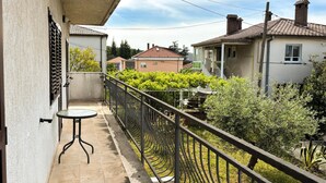 A balcony with a table, a metal railing, and a view of neighboring houses and greenery. - 3 bedroom amazing apartment in Kostrena (Kostrena)