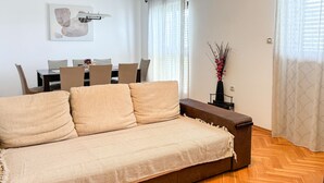 A living room with a sofa, a dining table with chairs, a vase with flowers, and a painting on the wall. - 3 bedroom amazing apartment in Kostrena (Kostrena)