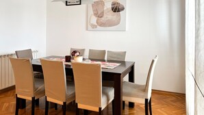 A dining area with a wooden table, six chairs, and a painting on the wall. - 3 bedroom amazing apartment in Kostrena (Kostrena)