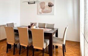 Ein Essbereich mit einem Holztisch, sechs Stühlen und einem Bild an der Wand.