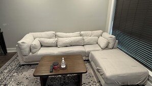 Uma sala de estar com um sofá modular, uma mesa de centro e um tapete estampado.