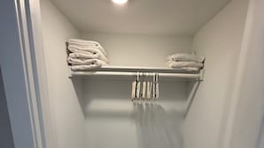 Um closet amplo com piso de madeira, paredes brancas e uma luminária no teto.