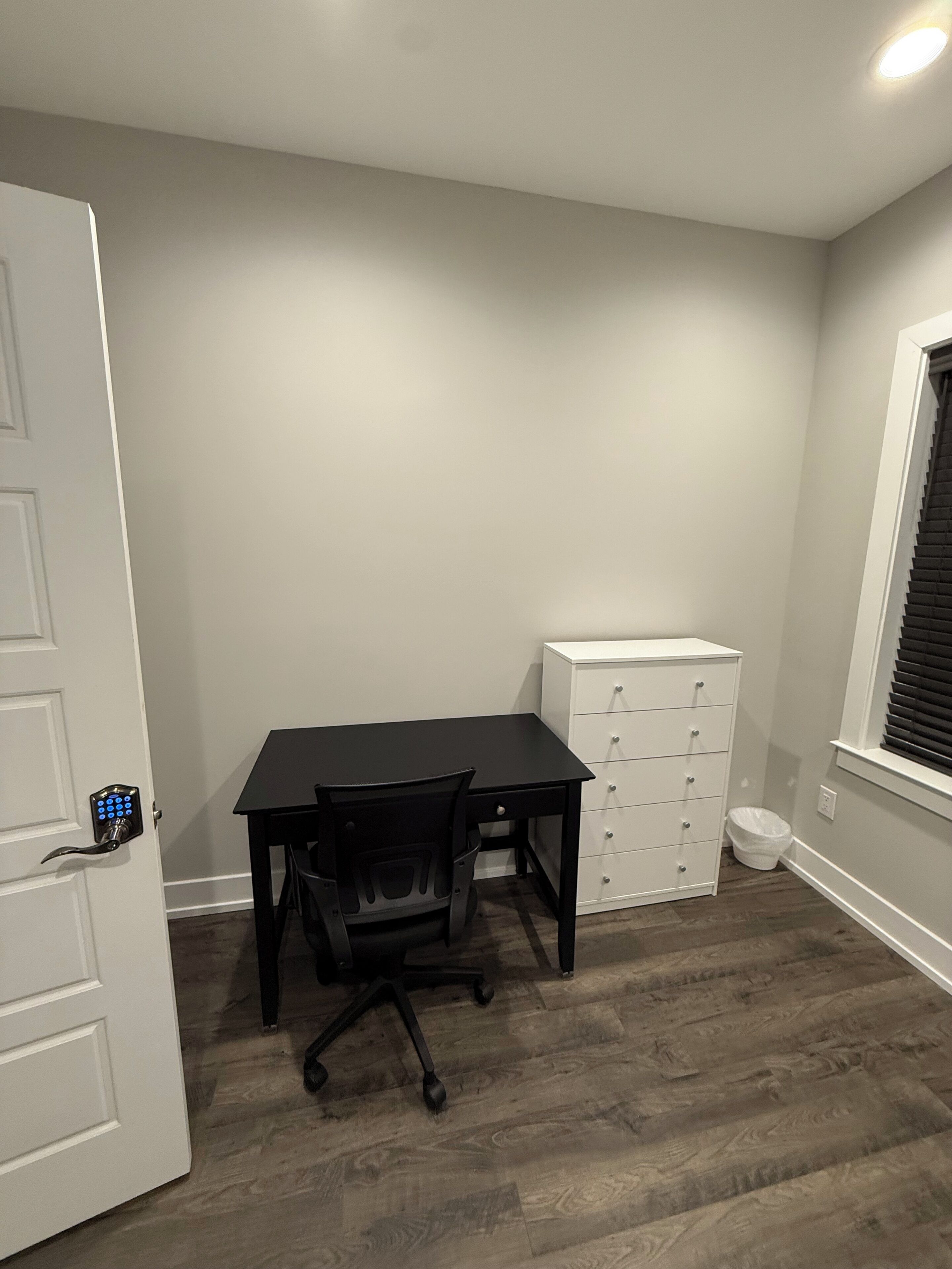 A room with a desk, chair, and a white storage unit.