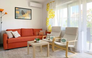 A living room with a sofa, a chair, a table, and a window with curtains.