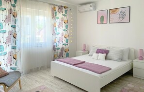 A bedroom with a bed, bedside tables, a chair, curtains, and wall art.