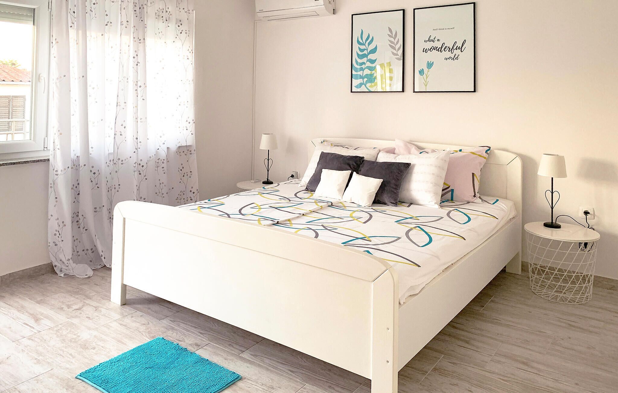 Un lit recouvert d’une couvre-lit à motifs, une table de chevet avec une lampe et deux œuvres d’art encadrées accrochées au mur.