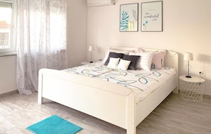 A bed with a patterned bedspread, a bedside table with a lamp, and two framed artworks on the wall. - Beautiful apartment in Krk with WiFi (Krk)