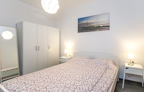 A bedroom with a bed, a wardrobe, a nightstand with a lamp, and a painting on the wall. - 1 bedroom nice apartment in Krk (Krk)