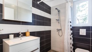 A bathroom with a white sink, a mirror, a shower, and a toilet. - Nice apartment in Krk with WiFi (Krk)