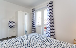 Ein Schlafzimmer mit Bett, Schrank, Fenster und Ausblick nach draußen.