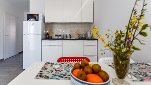 A modern kitchen with white cabinets, a refrigerator, and a dining area with a table set for two. - Nice apartment in Krk with WiFi (Krk)