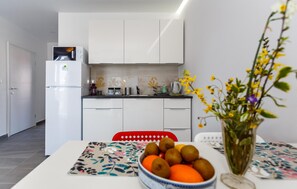 Eine moderne Küche mit weißen Schränken, einem Kühlschrank und einem Essbereich mit Tisch für zwei Personen.