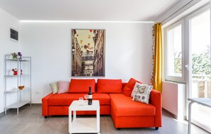 Ein modernes Wohnzimmer mit einem roten Sofa, einem weißen Couchtisch und einem großen Gemälde einer Stadtstraße.