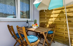 A wooden table with chairs, a bottle of wine, and a bowl of fruit. - Lovely apartment in Krk with WiFi (Krk)