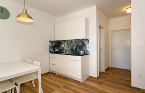 A modern kitchen with white cabinets, a black backsplash, and a wooden floor. - Lovely apartment in Krk with WiFi (Krk)