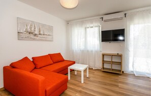 A living room with a sofa, a small table, a TV, and a painting on the wall. - Lovely apartment in Krk with WiFi (Krk)