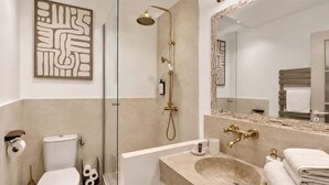 Ein modernes Badezimmer mit einer gläsernen Duschkabine, Toilette, Waschbecken mit großem Spiegel und Handtuchhalter.