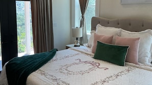 A bedroom with a bed, curtains, a nightstand, a lamp, and a painting on the wall. - Romantic 1-bedroom 2 bath french farmhouse with a polish of a high end hotel. (Three Rivers)