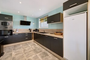 Eine moderne Küche mit integriertem Mikrowellenherd, Backofen und Spüle, mit dunklen Schränken und heller Arbeitsplatte.