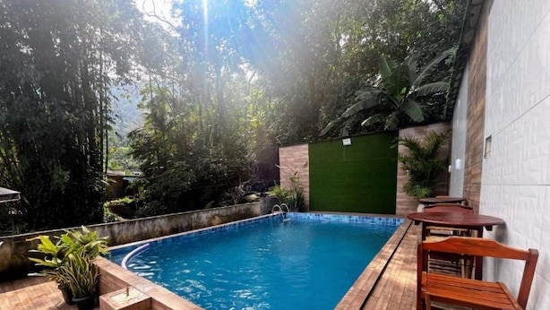 Piscina con cubierta de madera, rodeada de vegetación y un muro verde.