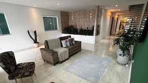 Un salón amplio con un sofá, sillones, una planta grande en maceta y un detalle decorativo en la pared.