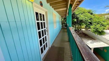 Un porche cubierto con puerta y ventanas, un banco de madera y vistas al follaje.