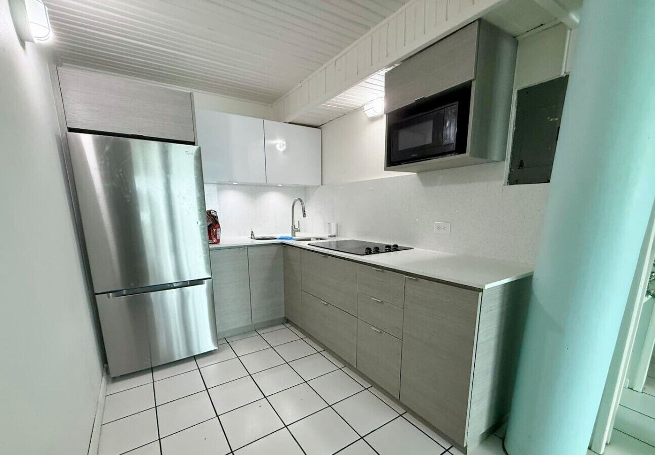 A kitchen with a stainless steel refrigerator, a microwave, and a sink.