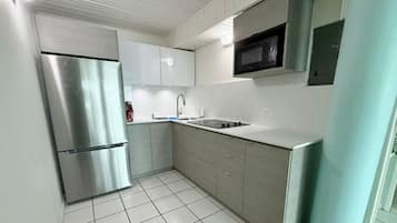 A kitchen with a stainless steel refrigerator, a microwave, and a sink.