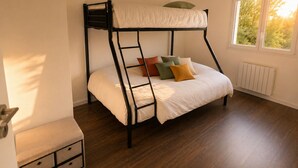A bunk bed with a ladder, a small bedside table with drawers, and a window with a view of trees. - Large house for 7 people on the outskirts of Brocéliande (Campénéac)