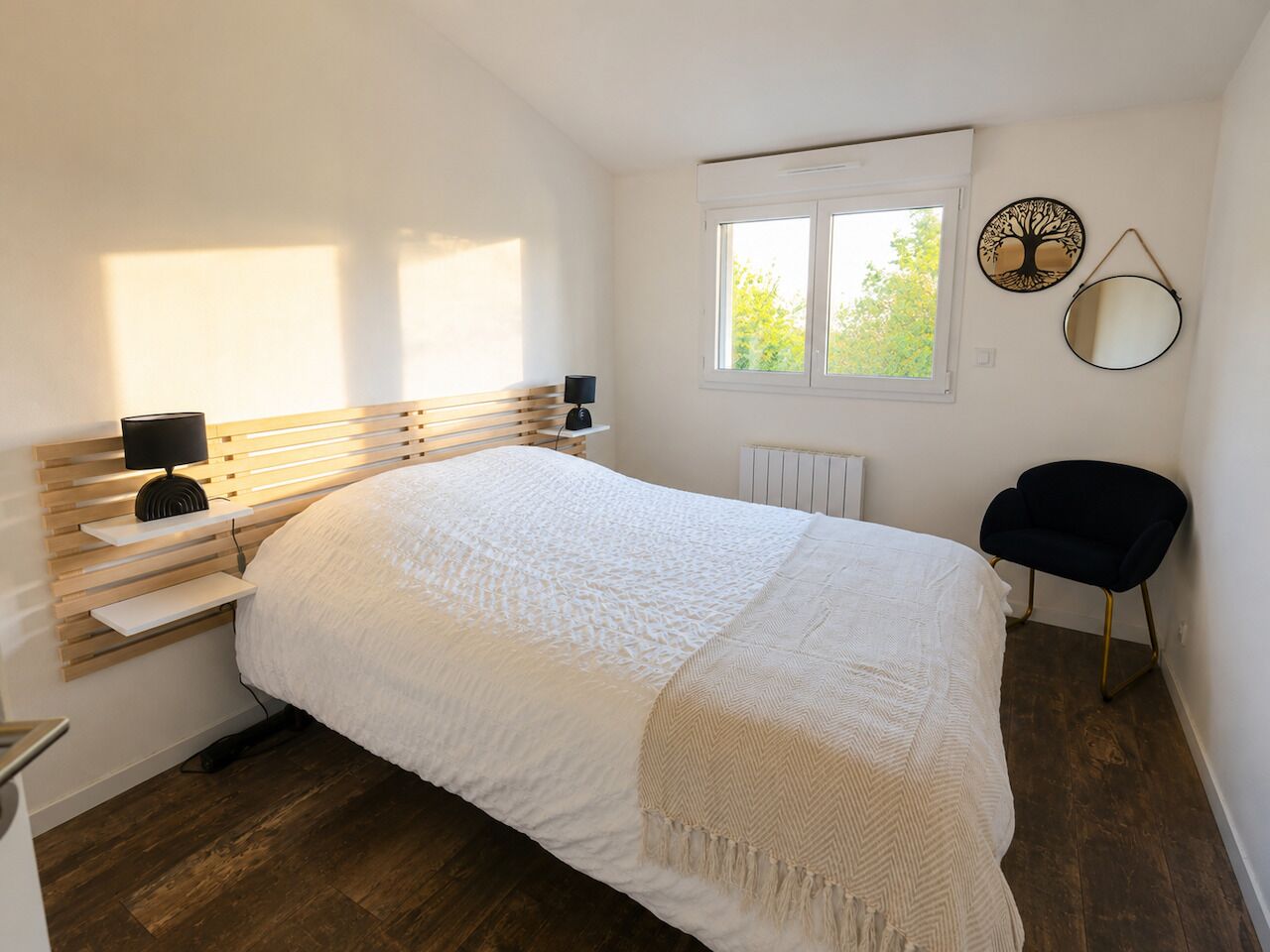 Une chambre à coucher comprenant un lit, des tables de chevet, une chaise, une fenêtre et des éléments de décoration murale.