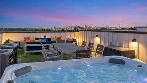 Terraza en la azotea con jacuzzi, zona de estar y vistas al horizonte de la ciudad.