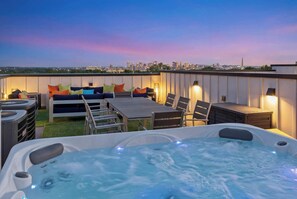 A rooftop terrace with a hot tub, seating area, and a city skyline view. - Sounds Like Fun- Hot Tub, Firepit, Mini Golf & Skyline Views, Near Broadway (Nashville)