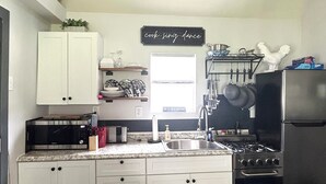 A kitchen with white cabinets, a stainless steel refrigerator, a gas stove, and a microwave. - Cottage in Bancroft countryside for the perfect relaxing getaway. (Bancroft)