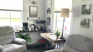 A living room with two grey sofas, a coffee bar, a dining table, and a lamp. - Cottage in Bancroft countryside for the perfect relaxing getaway. (Bancroft)