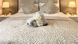 Una cama bien hecha con una colcha estampada, dos almohadas y un arreglo decorativo de flores.