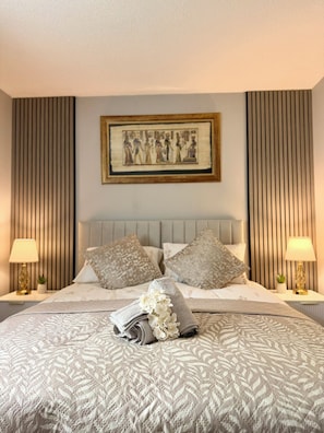 A neatly made bed with a patterned bedspread, two pillows, and a decorative arrangement of flowers. - Modern Central Aberdeen 2BR Apartment with Parking | Business & Leisure (Aberdeen)