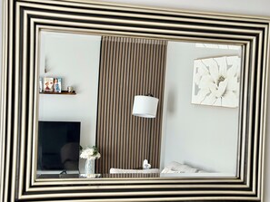 A room with a television, a lamp, a vase with flowers, a framed picture, and a striped wall. - Modern Central Aberdeen 2BR Apartment with Parking | Business & Leisure (Aberdeen)