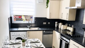 Una cocina moderna con comedor, piso de baldosas negras y ventana con persianas.