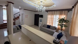 A living room with a sofa, a coffee table, a chandelier, and a staircase.