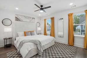 Ein Schlafzimmer mit einem Bett, einem Deckenventilator, einem Fenster mit Vorhängen, einer Heizung und einem karierten Teppich.