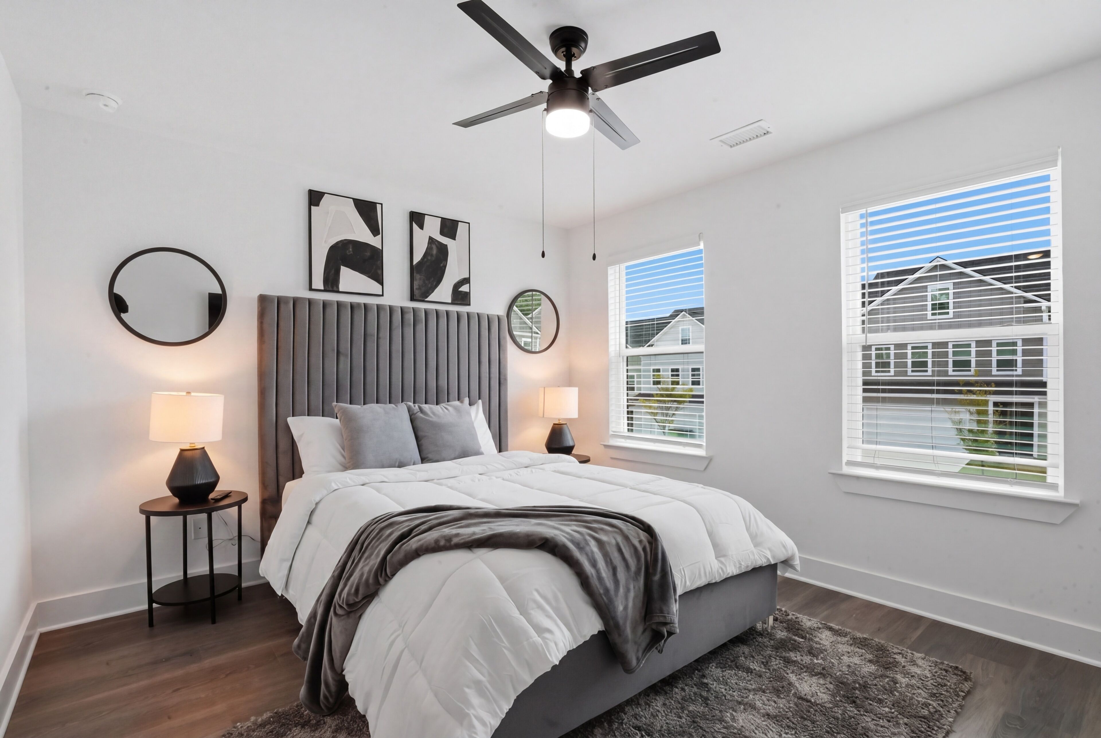 A bedroom with a bed, bedside lamps, a ceiling fan, and a window with blinds.