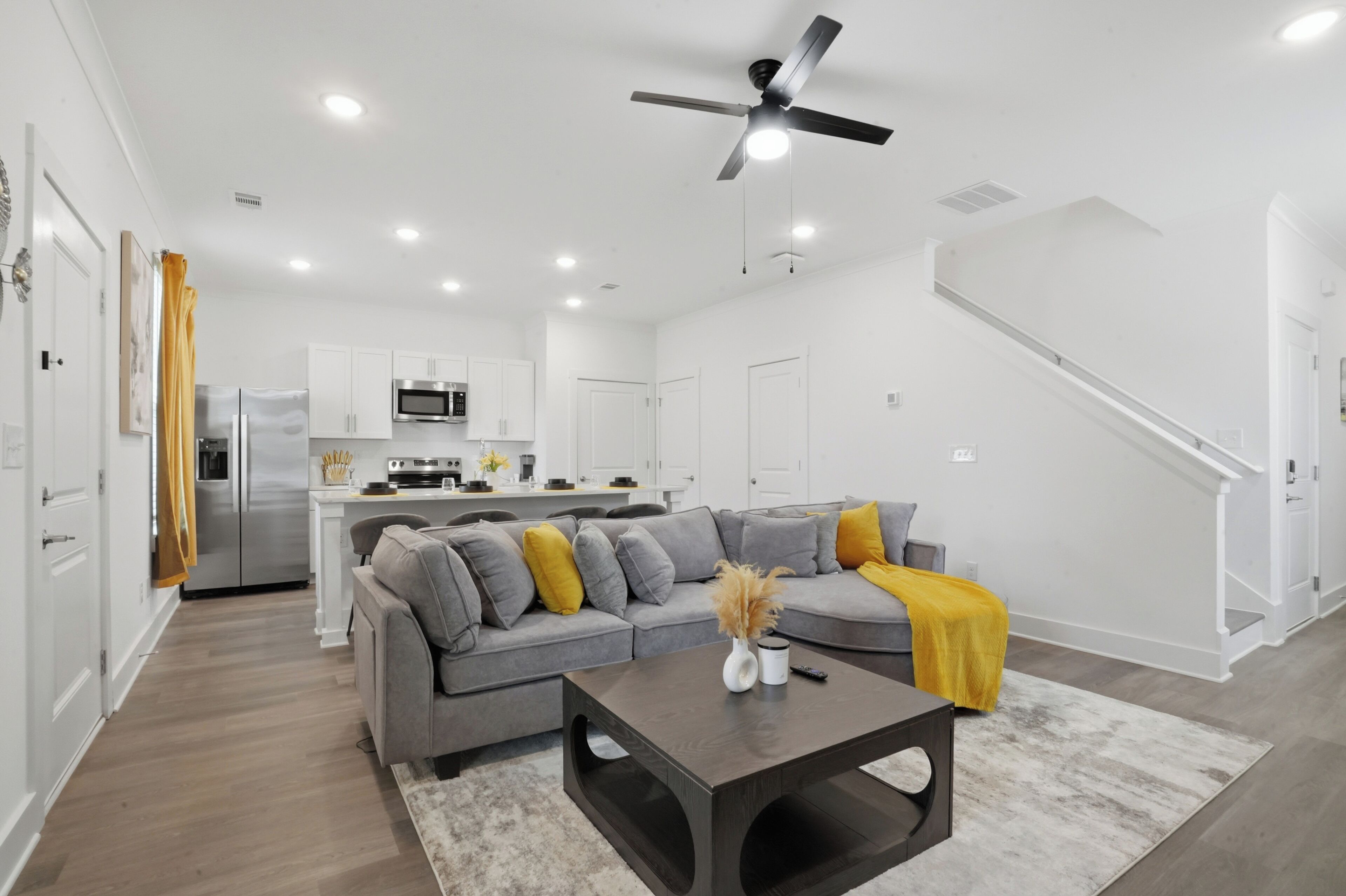 A modern living room with a grey sofa, a coffee table, and a ceiling fan.