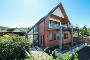 A modern house with a glass facade, a brick exterior, and a covered porch. - An outstanding, modern Annex with superb views- Pass the Keys (Stretton)